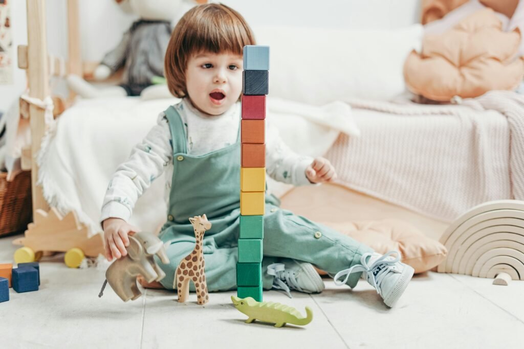 Adorable child playing with colorful wooden blocks and toy animals indoors.