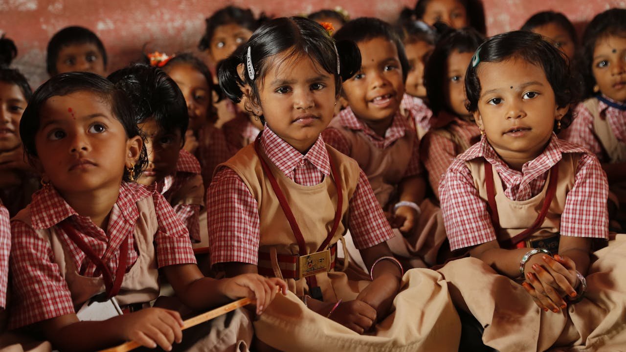 Group of young school children in uniforms sitting in a classroom, attentive and curious.