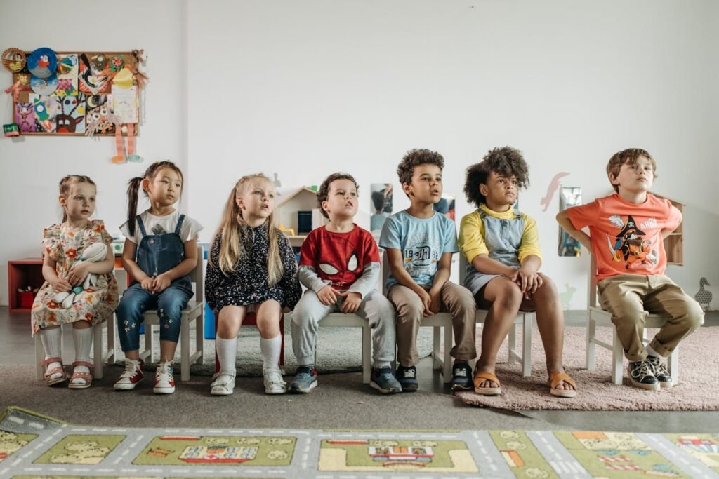 Children of different ethnicities sitting attentively in a classroom environment.
