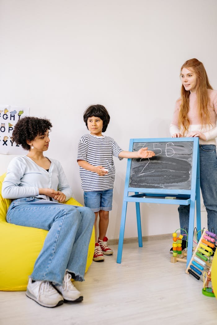 Children and teacher engaged in a learning activity with a chalkboard in a classroom.